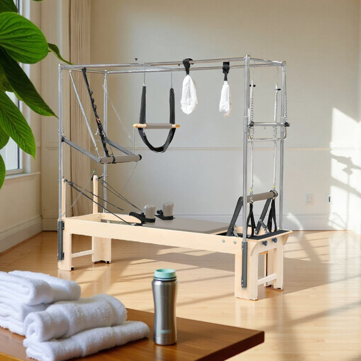 Elina Pilates Cadillac Reformer in a sunlit studio with folded towels and a plant