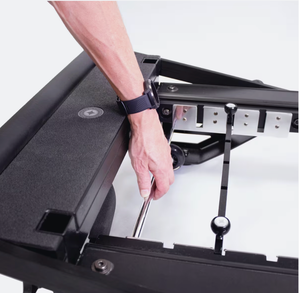Close-up of a hand adjusting the footbar settings on the Merrithew MPX Reformer Package