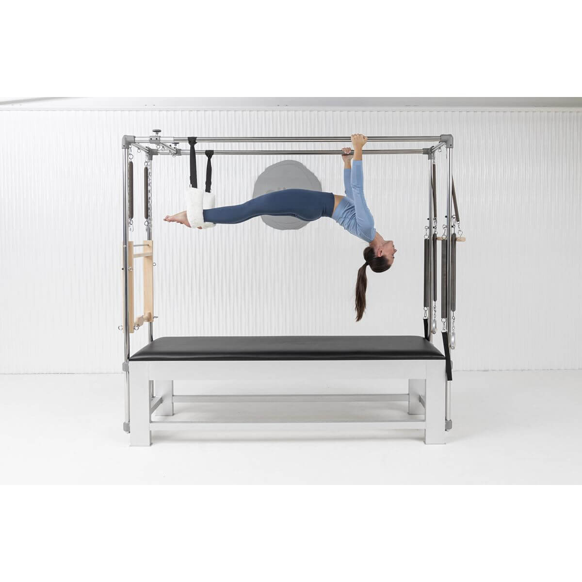 Woman performing an inverted hang on the Elina Pilates Classic Aluminium Cadillac in a white studio