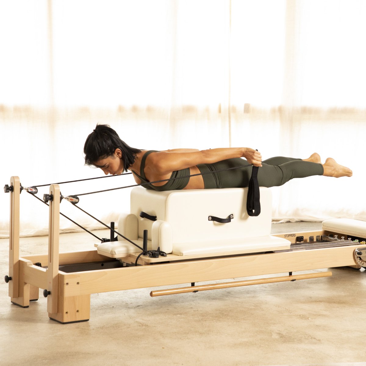 Woman performing a swimming exercise over the box on the Elina Pilates Lignum Reformer