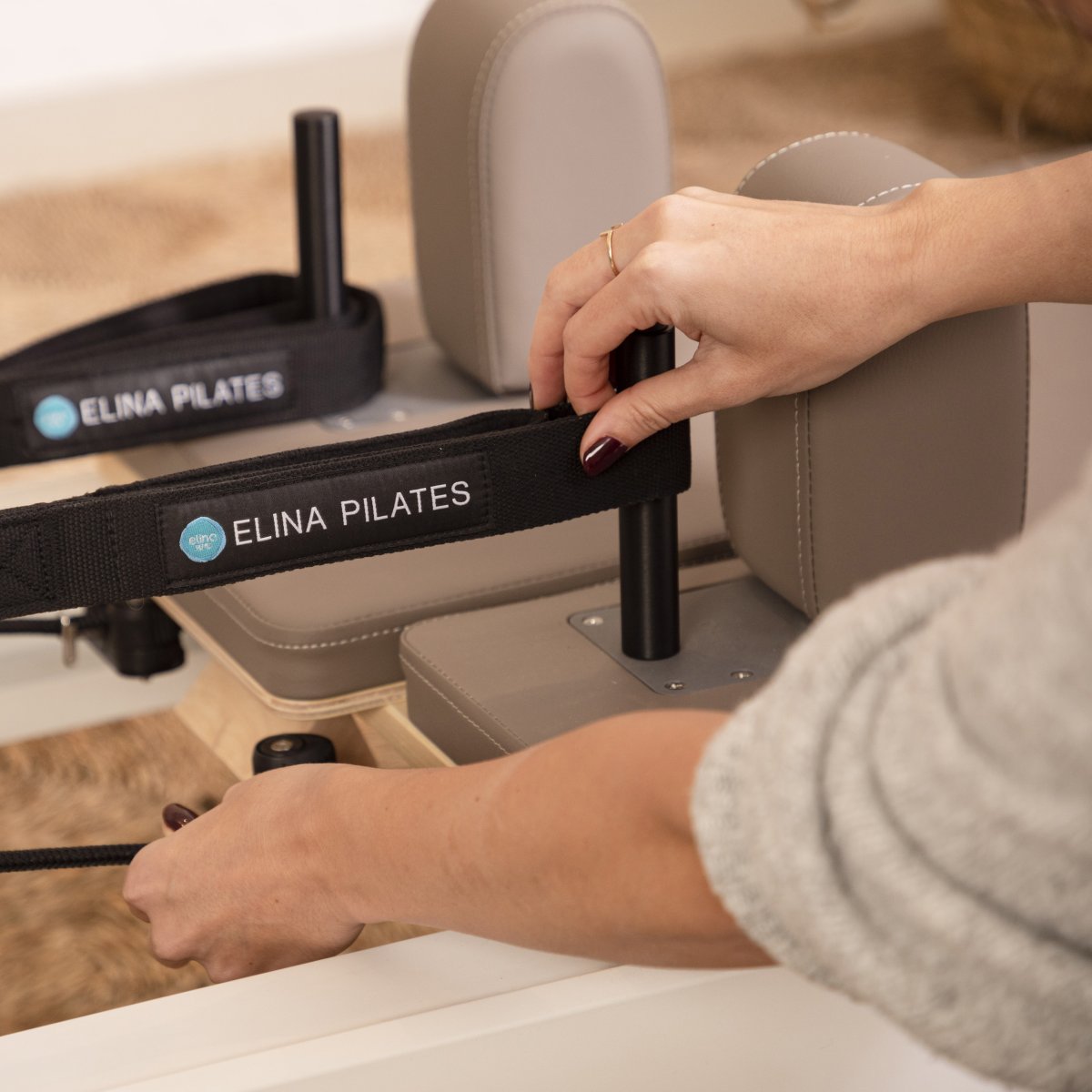 Hands adjusting the headrest height on the Elina Pilates Nubium Reformer